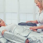Manuální vs. Přístrojová Lymfodrenáž: Která Se Vyplatí? 9 a woman receiving manual lymphatic drainage treatment while lying on a specialized massage table with a therapist assisting