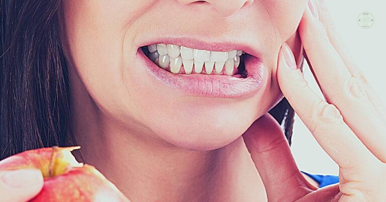 a person holding their cheek while smiling to show tooth sensitivity or pain during biting, highlighting exposed gum area.