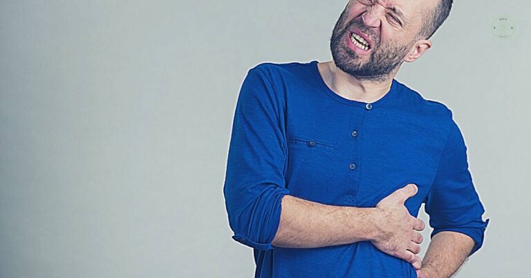 a man clutching his right side under the ribcage, grimacing in apparent pain.
