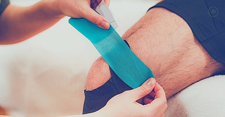 a person applying kinesio-taping on an athlete’s elbow with a green tape and spray adhesive.