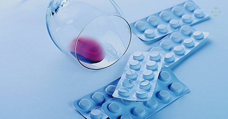 a glass of red wine spilling next to blister packs of pills, illustrating dangerous drug-alcohol interaction