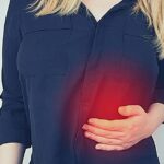 a person holding their right side under the ribs indicating discomfort or pain near the area associated with potential píchání pod pravým žebrem