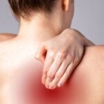7 Hlavních Příčin Bolesti Zad Mezi Lopatkami & Jak Si Pomoci Od Bolesti! 7 a person holding their right shoulder and upper back area showing signs of muscle tension or pain between the shoulder blades