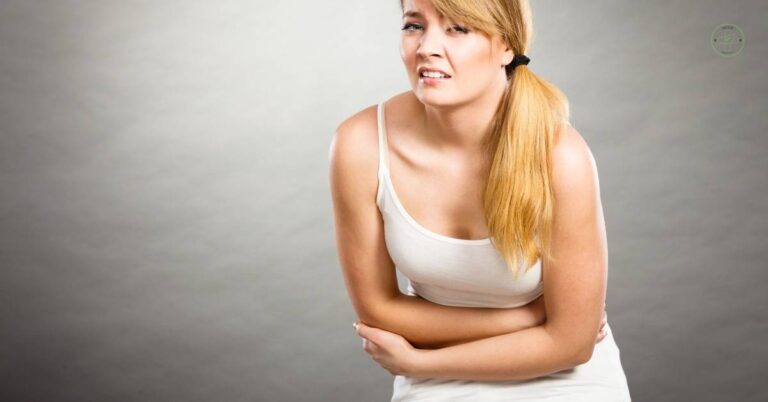 a woman clutching her abdomen in apparent discomfort, suggesting abdominal pain or křeče v břiše