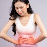 Jak Vyzrát Na Bolest Břicha Po Jídle! Víme Co Vám Pomůže! 7 a person holding her stomach in discomfort, highlighting abdominal pain after eating.