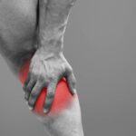 Trápí Vás Bolest Lýtka Zezadu? Známe Příčinu i Léčbu! 5 a person holding their lower back and upper leg area highlighting pain in the posterior thigh region near the hamstring muscle