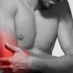 a person holding their left arm and upper shoulder area highlighted in red indicating potential bolest levé ruky and associated discomfort.