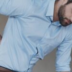 6 Nejlepších Mastí Na Bolesti Zad, Které Jsou Volně Prodejné! 7 a man experiencing back pain, holding his lower back while leaning forward