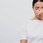a person covering their eyes with their hand, indicating discomfort or irritation from suché oči or únava očí.