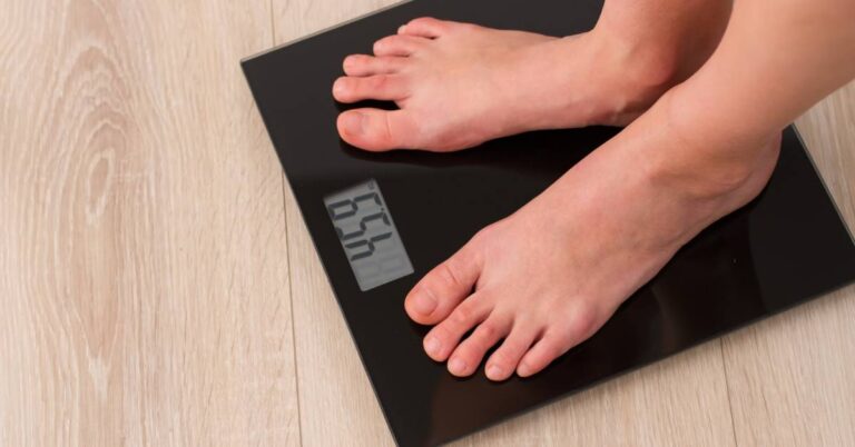 a person standing barefoot on a digital bathroom scale measuring body weight for calculating ideal weight based on height and gender.