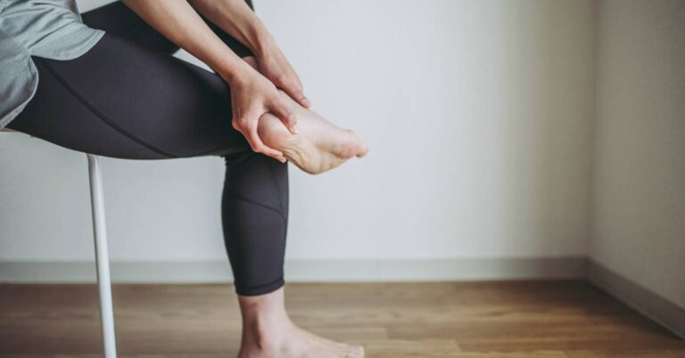 a person performing a self-massage of the foot arch and heel to alleviate heel pain, focusing on plantar area relief.