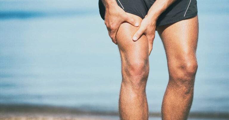 a person holding their knee in apparent pain, highlighting potential symptoms of leg discomfort near the joint.