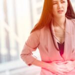 a woman holding her lower abdomen in apparent discomfort, possibly indicating symptoms related to ovarian cyst pain