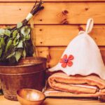 Jak správně používat infrasaunu: Praktický návod pro začátečníky 6 a wooden bench with infrasauna towel, wooden bucket of birch branches, and handcrafted sauna accessories on rustic background