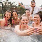 a group of people enjoying a hot tub with champagne glasses, celebrating in an outdoor setting.