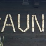 9 Překvapivých Účinků Infrasauny Na Zdraví: Vše, co potřebujete vědět 3 birch log spelling "SAUNA" on a dark wooden wall, highlighting natural saunování ambiance