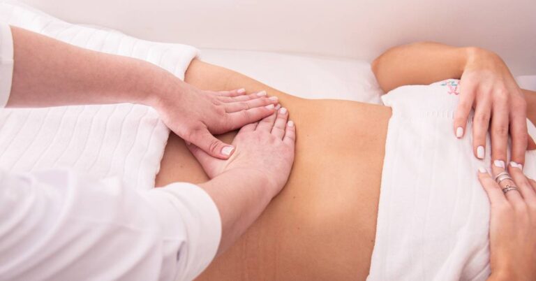 a person receiving manual lymphatic drainage massage on the abdomen with gentle hand techniques.
