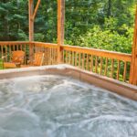 Jak na zastřešení vířivky: Návod pro snadné a účinné krytí vaší relaxační zóny 8 a wooden deck with a hot tub surrounded by a railing, featuring wicker chairs and lush greenery, ideal for a relaxed outdoor relaxation zone under natural shade.