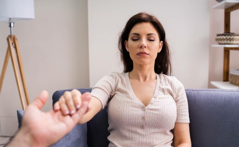 a woman in relaxed seated position practicing deep breathing or mindfulness, embodying empathy and acceptance during a therapeutic session.